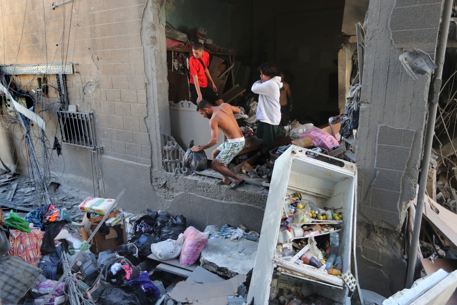 Lebanese citizens collect their belongings from their destroyed apartment that was hit by an Israeli airstrike, in Tyre, south Lebanon, Thursday, Oct. 24, 2024. (AP Photo/Mohammed Zaatari)