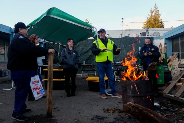 Boeing employees gather around a burn barrel as others arrive to vote on a new contract offer from the company Monday, Nov. 4, 2024, at the Aerospace Machinists Union hall in Renton, Wash. (AP Photo/Lindsey Wasson)