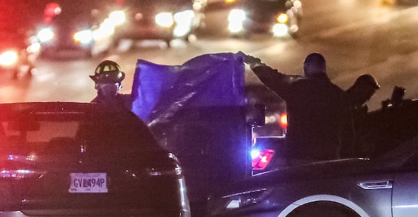 Cobb County authorities place a tarp over a body lying in the 6600 block of Mableton Parkway early Tuesday.