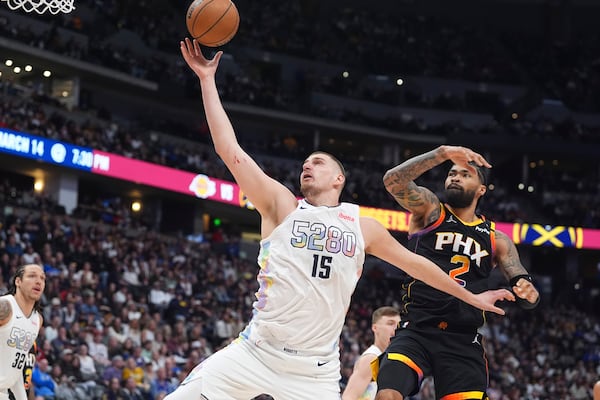 Denver Nuggets center Nikola Jokic (15) pulls in a rebound as Phoenix Suns center Nick Richards defends in the second half of an NBA basketball game Friday, March 7, 2025, in Denver. (AP Photo/David Zalubowski)