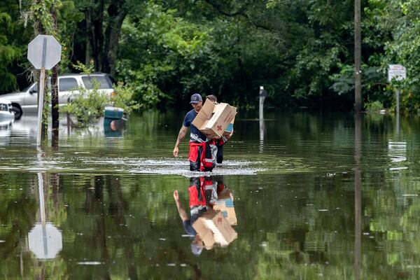 Savannah Fire advanced firefighters Andrew Stevenson (front) and Ron Strauss carry food to residents in the Tremont Park neighborhood that where stranded in flooding from Hurricane Debby on Tuesday, Aug. 6, 2024, in Savannah, Ga. (Stephen B. Morton/AP)