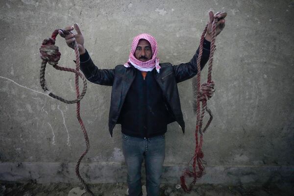 A man holds up two ropes tied in the shape of nooses, found in the infamous Saydnaya military prison, just north of Damascus, Syria, Monday, Dec. 9, 2024. Crowds are gathering to enter the prison, known as the "human slaughterhouse," some hoping to find relatives who were held there, after thousands of inmates were released following the rebels' overthrow of Bashar al-Assad's regime on Sunday. (AP Photo/Hussein Malla)