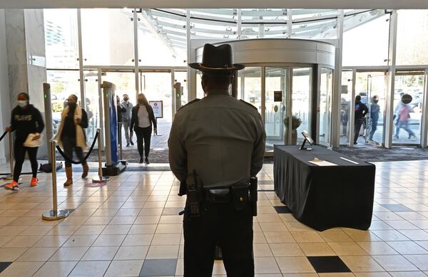 Security monitors shoppers as they walk through metal detectors at Lenox Square in December. (Hyosub Shin / Hyosub.Shin@ajc.com)