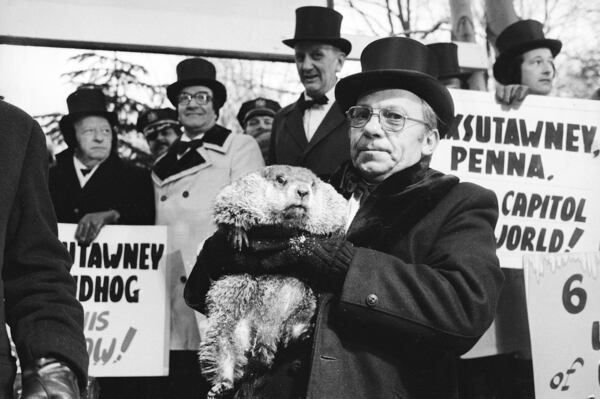 FILE - Jim Means holds up Punxsutawney Phil at daybreak, Feb. 2, 1980, in Punxsutawney, Penn., in front of a crowd of anxious people. (AP Photo, File)