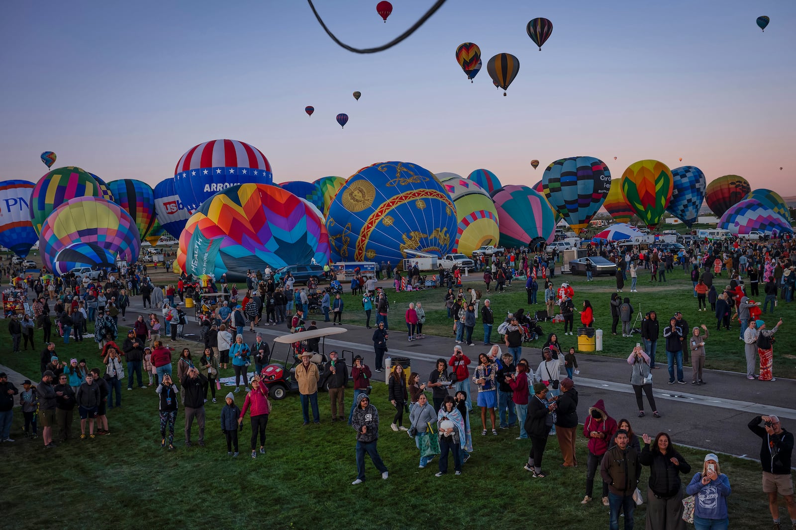 People watch as Meow Wolf's Skyworm hot air balloon takes flight during the Albuquerque International Balloon Fiesta at Balloon Fiesta Park in Albuquerque, N.M., on Tuesday, Oct. 8, 2024. (Chancey Bush/The Albuquerque Journal via AP)