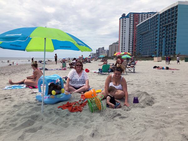 Christy Kasler, center, from Ohio, enjoys a day at the beach,  while her daughter-in-law Cory plays with her grandson, Bentley, in Myrtle Beach.