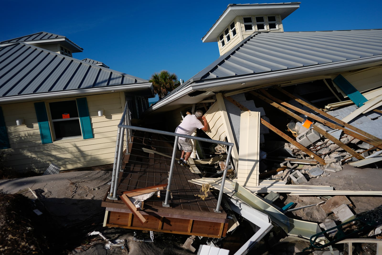 A property owner who preferred not to give his name peers into the remains of the second floor unit where he lived with his wife while renting out the other units, on Manasota Key, in Englewood, Fla., following the passage of Hurricane Milton, Sunday, Oct. 13, 2024. (AP Photo/Rebecca Blackwell)