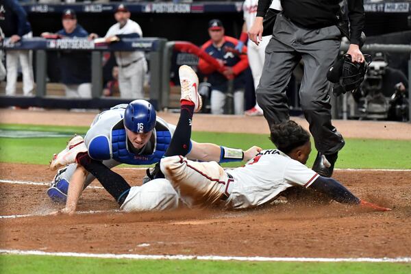 Braves second baseman Ozzie Albies (1) slides into home plate to score the game-tying run ahead of the tag of Los Angeles Dodgers catcher Will Smith during the eighth inning pf Game 2 of the NLCS Sunday, Oct. 17, 2021, at Truist Park in Atlanta. (Hyosub Shin / Hyosub.Shin@ajc.com)