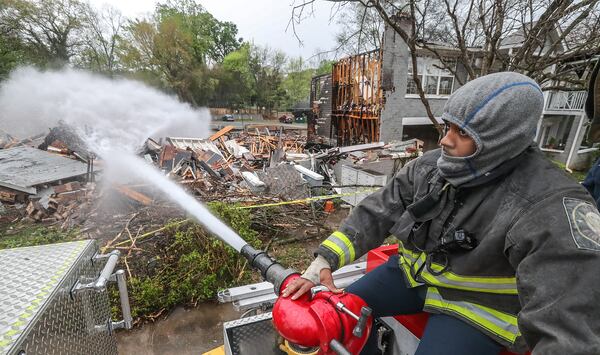 Atlanta firefighter Jamar Sims douses hot spots at the North High Ridge Apartments on Monday morning, more than 24 hours after a fire destroyed the historic building.