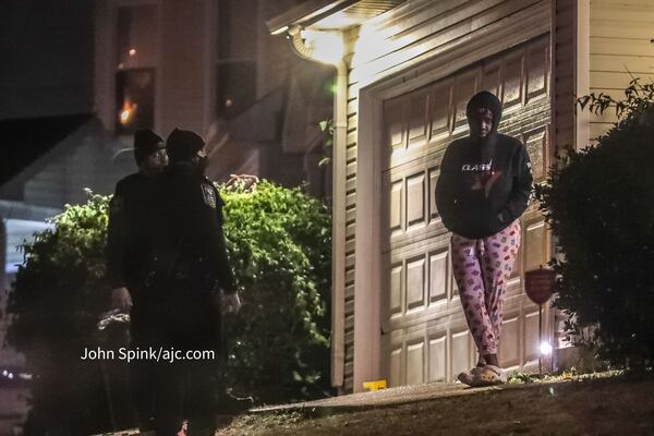 Police speak to a person in the Woods of Wellborn neighborhood near Lithonia after an early morning shooting.