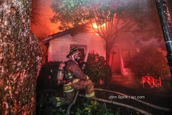 A Hapeville firefighter works to put out a  house fire on Lavista Drive Tuesday morning. JOHN SPINK / JSPINK@AJC.COM