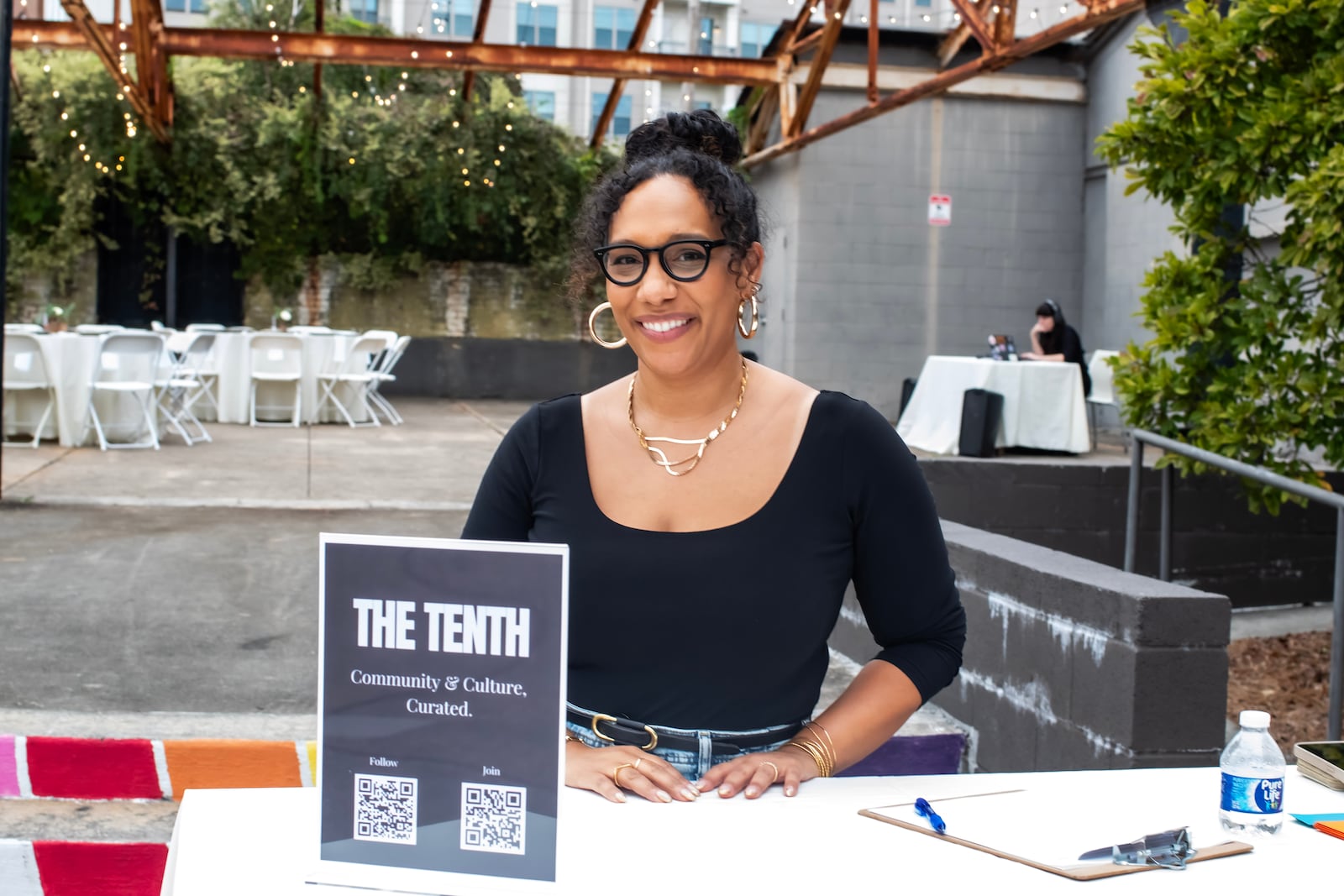 Nasim Fluker sits behind a table welcoming guests to an event for members of The Tenth.