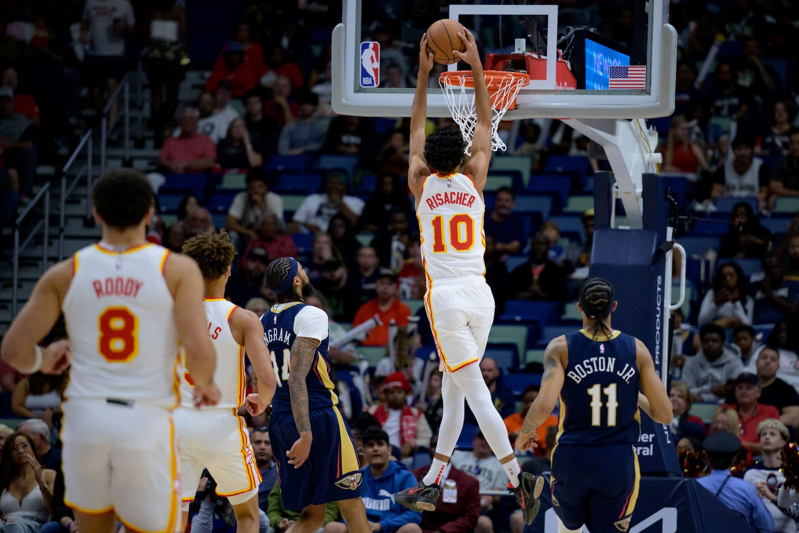 Atlanta Hawks forward Zaccharie Risacher (10) dunks next to New Orleans Pelicans forward Brandon Ingram (14) during the first half of an NBA basketball game in New Orleans, Sunday, Nov. 3, 2024. (AP Photo/Matthew Hinton)