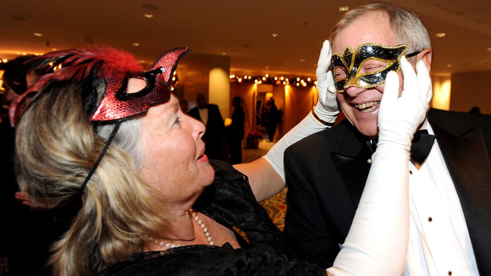 Patricia DeWilde adjusts the mask for her husband Dick as they join the parade of stars at the Marriott Marquis for the annual Mayor's Masked Ball to benefit the UNCF on Saturday, Dec. 21, 2013, in Atlanta. David Tulis / AJC