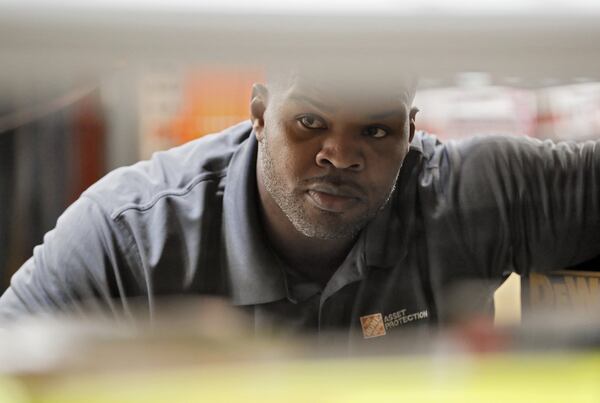 Paul McKinley, a Home Depot asset protection specialist, watches the power tool aisle from behind display shelving. Bob Andres / robert.andres@ajc.com