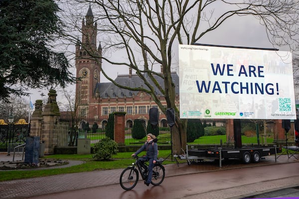 Activists put up a billboard outside the International Court of Justice, in The Hague, Netherlands, as it opens hearings into what countries worldwide are legally required to do to combat climate change and help vulnerable nations fight its devastating impact, Monday, Dec. 2, 2024. (AP Photo/Peter Dejong)