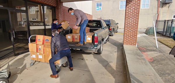 Four elementary schools in Lawrenceville were excited to receive books for their students from the First Book Club 165 of Lawrenceville First Baptist Church. Pictured are: Senior Pastor Inman Houston, standing in the truck, receiving a box from Logan Ferrell, student ministry director. Associate Pastor Radu Calibu is in front. (Courtesy of Vicki Aiken)