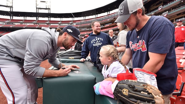 Braves' Charlie Culberson signs an autograph for Aria Dollars, 4, as her father Jason Dollars (right) holds her before the start of the Game 3 of the Division Series between the Braves and Cardinals Sunday, Oct. 6, 2019, at Busch Stadium in St. Louis.