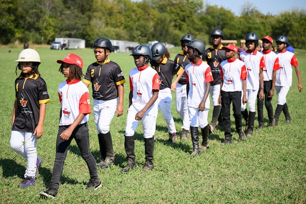 Members of the B.E.S.T Academy polo team (red and white) and their opponents from the Congressional Polo Club (black and gold) march onto the field to start their match at the 7th Annual Atlanta Fashion and Polo Classic on Sunday, Oct. 13, 2024, in Fairburn, GA. (Jim Blackburn for the AJC)