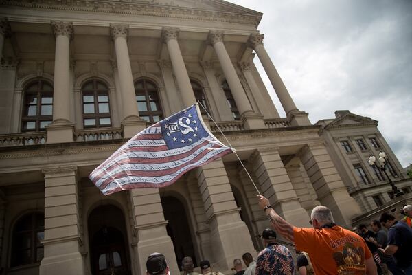 David Moor holds up a flag at a gun rights rally at the  state Capitol in Atlanta on Saturday, April 14, 2018.  STEVE SCHAEFER / SPECIAL TO THE AJC