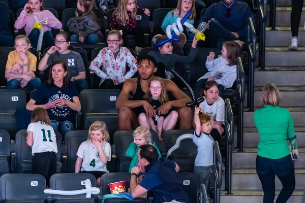 Georgia Tech center James Banks watches a Yellow Jackets women's basketball game with Mazie Ruth Thomas, 10, daughter of Tech assistant athletic director of Leah Thomas (to their right). (Danny Karnik/Georgia Tech Athletics)