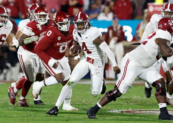 Alabama quarterback Jalen Milroe (4) runs the ball beside Oklahoma defensive lineman David Stone (0) during the second quarter of a NCAA college football game Saturday, Nov. 23, 2024, in Norman, Okla. (AP Photo/Alonzo Adams)