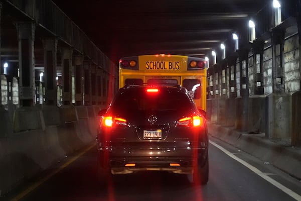 Ironically, PiggyBack Network co-founder and CEO Ismael El-Amin drives his car behind a Chicago Public Schools bus as on this day he will take three children, including one of his own, to various schools as part of the PiggyBack ride-share network Thursday, Oct. 10, 2024, in Chicago. (AP Photo/Charles Rex Arbogast)