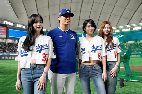 Los Angeles Dodgers pitcher Yoshinobu Yamamoto, middle left, poses for photos with members of MISAMO, a subunit of the K-pop girl group TWICE, before an MLB Japan Series exhibition baseball game between the Dodgers and the Hanshin Tigers, Sunday, March 16, 2025, in Tokyo. (AP Photo/Eugene Hoshiko)