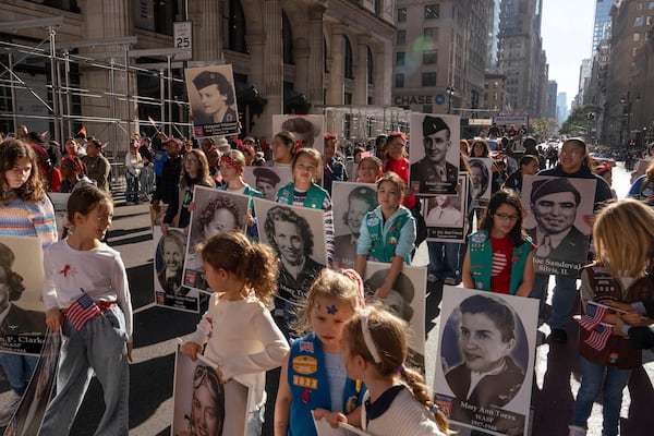 Girl Scouts carry photographs of people who served in World War II during the annual Veterans Day Parade, Monday, Nov. 11, 2024 in New York. (AP Photo/Adam Gray)