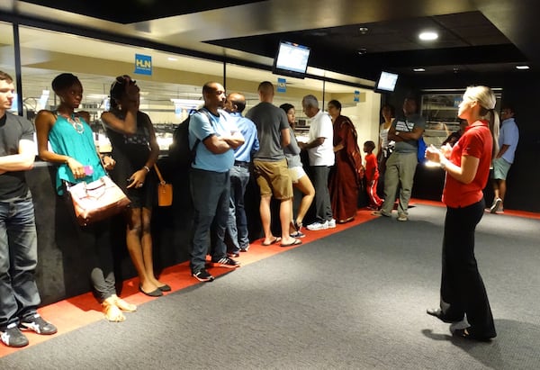 CNN Inside Studio Tour guide Lindsay Walker (right) gives tourists statistics in a space overlooking HLN’s newsroom. (Rodney Ho / rho@ajc.com)