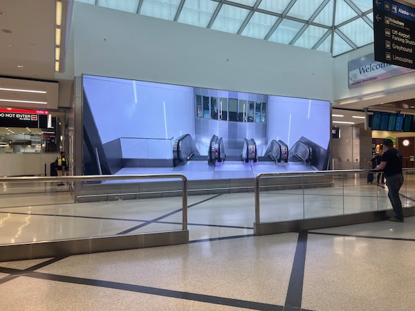 A screen now shows a video of the top of the escalators at Hartsfield-Jackson International Airport's west crossover. (Kelly Yamanouchi/AJC)