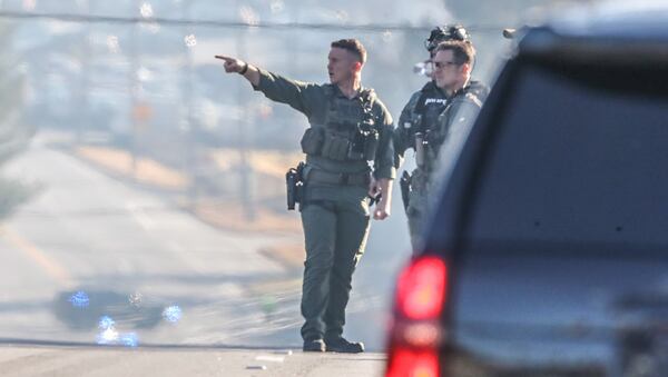 Officers in tactical gear join the search for a suspect accused of shooting two DeKalb County sheriff's investigators Wednesday morning.