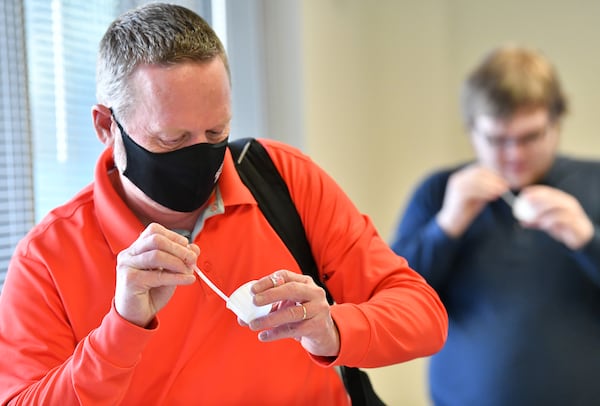 Donald Smith (foreground) and his son Jacob Smith, both Georgia Tech employees, collect their saliva samples for PCR COVID-19 tests at Georgia Tech’s Economic Development Building on Tuesday, Jan. 4, 2022. Rommi Kashlan, a student in its College of Sciences, was part of the team that developed the test. (Hyosub Shin / Hyosub.Shin@ajc.com)