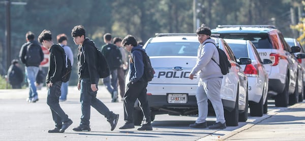 Norcross High students change classes Thursday morning as police vehicles line the school parking lot after Wednesday's off-campus shooting.