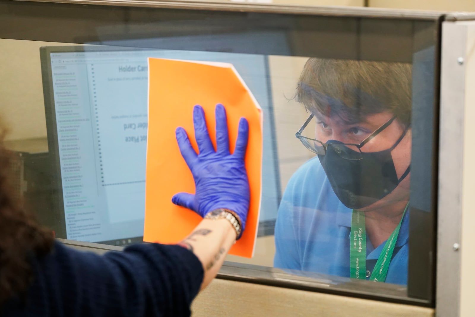 FILE - Andrew Hougardy, a worker at the King County election headquarters in Renton, Wash., views an "alternative format" ballot held up by a co-worker during ballot processing and counting, Friday, Oct. 23, 2020. (AP Photo/Ted S. Warren, File)