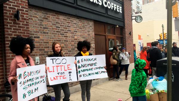 Protesters gather outside a Starbucks in Philadelphia, Sunday, April 15, 2018, where two black men were arrested Thursday after Starbucks employees called police to say the men were trespassing. The arrest prompted accusations of racism on social media. Starbucks CEO Kevin Johnson posted a lengthy statement Saturday night, calling the situation "disheartening" and that it led to a "reprehensible" outcome. (AP Photo/Ron Todt)