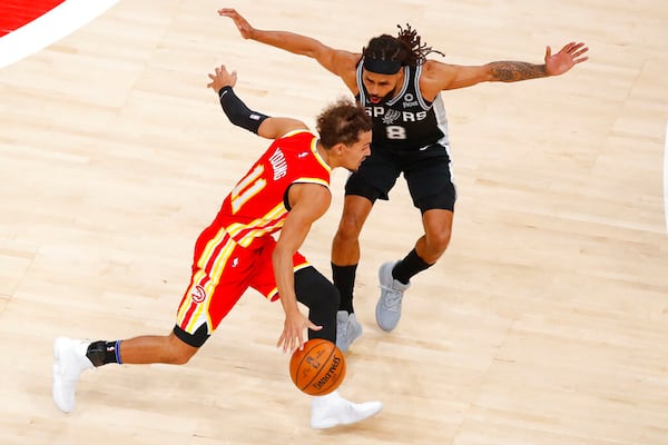 Atlanta Hawks guard Trae Young (11) drives against San Antonio Spurs guard Patty Mills (8) during the first half of an NBA basketball game on Friday, Feb. 12, 2021, in Atlanta. (AP Photo/Todd Kirkland)