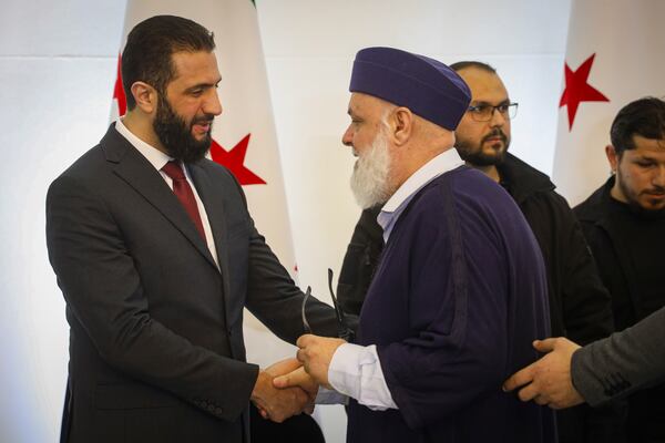 Syria's interim president Ahmad al-Sharaa, left, greets delegates during Syria's national dialogue conference at the People's Palace in Damascus, Syria, Tuesday Feb. 25, 2025. (AP Photo/Omar Albam)