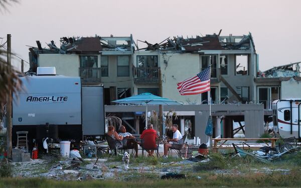 Jaques and Bela Sebastiao of Mexico Beach, living in a camper trailer parked on the slab where their former home stood, fly the American flag from the rubble while gathering with neighbors Larry Burks and Bob Coleman seven months after Hurricane Michael destroyed 80% of the homes in Mexico Beach on Florida’s Gulf Coast. The Sebastiao are some of the few who have returned permanently, while their neighbors visit on weekends staying in campers where their homes once stood. All are still waiting to rebuild. 