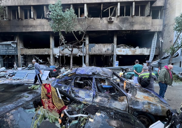 People gather in front of destroyed shops that were hit Sunday evening in an Israeli airstrike in central Beirut, Lebanon, Monday, Nov. 18, 2024. (AP Photo/Hussein Malla)