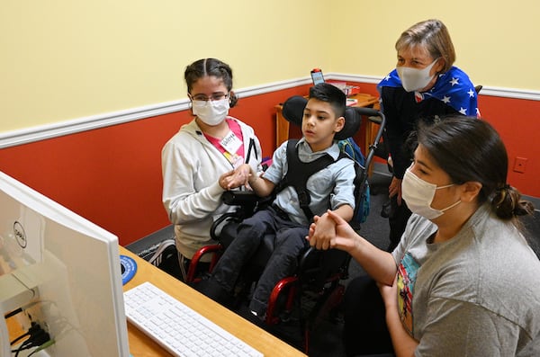 A summer camp participant Brandon, 7, plays a video bowling game using eye tracker technology as his sister Valerya (left), 14, Helene Prokesch, Founder and Executive Director, and Mia Vahle (right), Lekotek Leader, help during a summer camp for children with special needs at Lekotek of Georgia in Tucker on Tuesday, July 12, 2022. (Hyosub Shin / Hyosub.Shin@ajc.com)