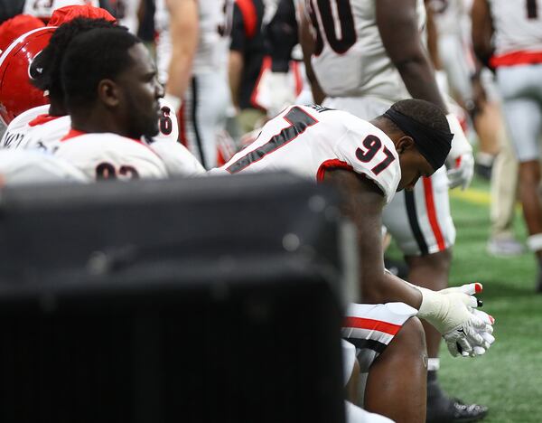 Georgia defensive lineman Warren Brinson (right) sits dejected with teammates on the sidelines duri\ng the final minutes of a 41-24 loss to Alabama in the SEC Championship game on Saturday, Dec 4, 2021, in Atlanta.   “Curtis Compton / Curtis.Compton@ajc.com”`