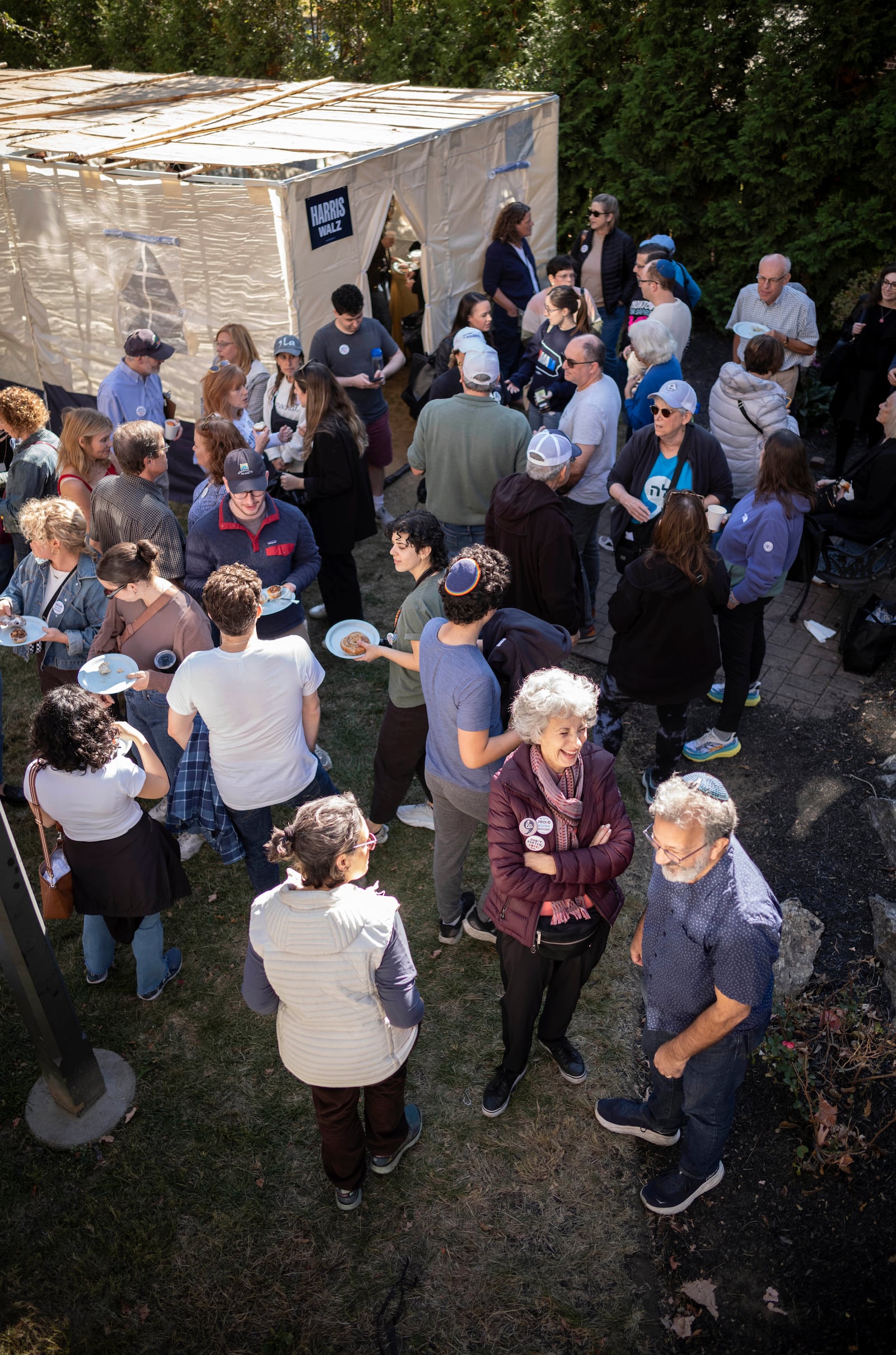 Supporters of Democratic presidential nominee Vice President Kamala Harris gather around a Sukkot before going door to door canvassing Jewish voters during the Jewish holiday in Bala Cynwyd, Pa, Sunday, Oct. 20, 2024. (AP Photo/Laurence Kesterson)