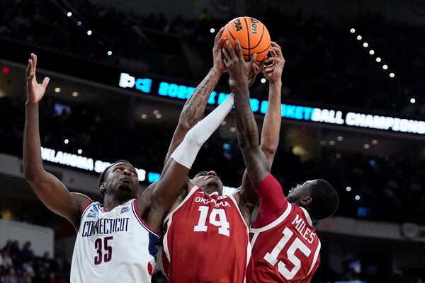 Oklahoma forward Jalon Moore (14) grabs the rebound against UConn center Samson Johnson (35) with an assist from guard Duke Miles (15) during the first half in the first round of the NCAA college basketball tournament, Friday, March 21, 2025, in Raleigh, N.C. (AP Photo/Stephanie Scarbrough)