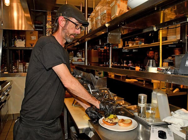 Chef Brian Hill assembles a Pepper Jack Loves Fraggle Rock Smash Burger in the kitchen of Local Republic. (Chris Hunt for the AJC)