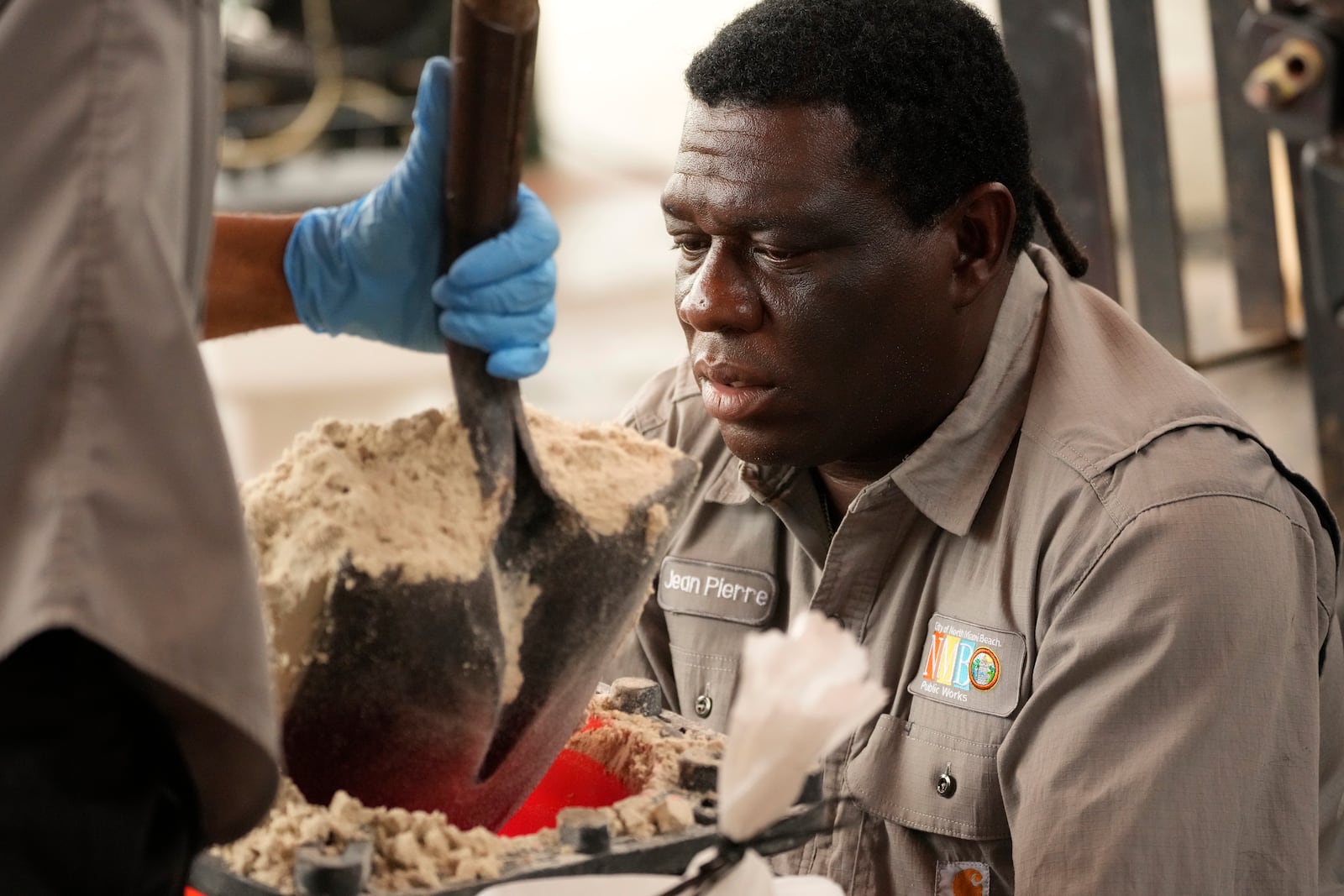 North Miami Beach, Fla., public service worker Jean Pierre Amisial Louis holds a sandbag as workers load sandbags, to be distributed to residents as Hurricane Milton prepares to strike Florida, Tuesday, Oct. 8, 2024, in North Miami Beach. (AP Photo/Wilfredo Lee)