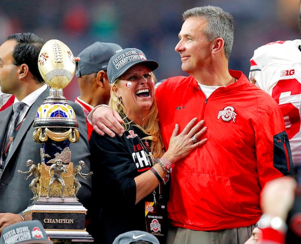 FILE - In this Jan. 1, 2016, file photo, Ohio State head coach Urban Meyer hugs his wife, Shelley, after their 44-28 win over Notre Dame in the Fiesta Bowl NCAA college football game, in Glendale, Ariz. Ohio State placed Meyer on paid administrative leave Wednesday, Aug. 1, 2018, while it investigates claims that his wife knew about allegations of abuse against former Buckeyes assistant Zach Smith, who was fired last week. (AP Photo/Rick Scuteri, File)