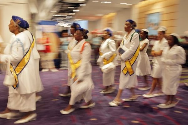 Ladies who are part of the Knights and Ladies of St. Peter Claver enter the hall.