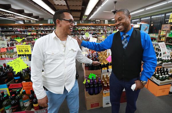 Erick Ferguson (right), a witness in a New Year’s Eve officer-involved shooting, gets a hug from store owner Elias Gebi while discussing how close he came to being hit by the bullets during an interview where the incident occurred at Big John's Package Store on Monday in Stone Mountain.    CURTIS COMPTON / CCOMPTON@AJC.COM