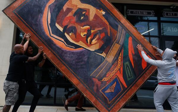 People help place J.R. Outlaw art piece outside of Takeoff which was recognized as world's largest tattoo by Guinness World Records at Atlanta Ink in Atlanta on July 5, 2023. (Michael Blackshire/Michael.blackshire@ajc.com)